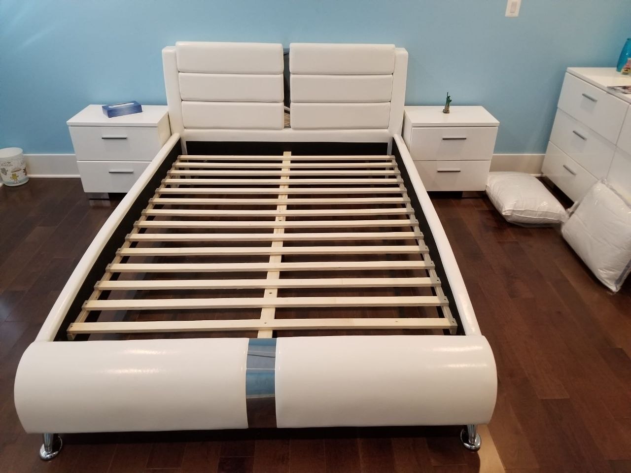 Upholstered bed frame with exposed slats during assembly